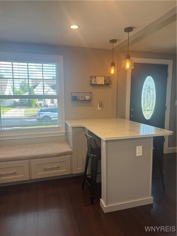 149 Wrexham Ct S, Tonawanda, NY 14150 - kitchen featuring a peninsula, a breakfast bar, white cabinets, dark wood-style floors, and light stone counters
