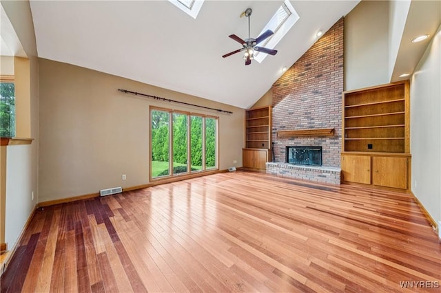 100 Hunt Club Cir, Amherst, NY 14051 - unfurnished living room featuring a skylight, a brick fireplace, hardwood / wood-style flooring, high vaulted ceiling, and built in features