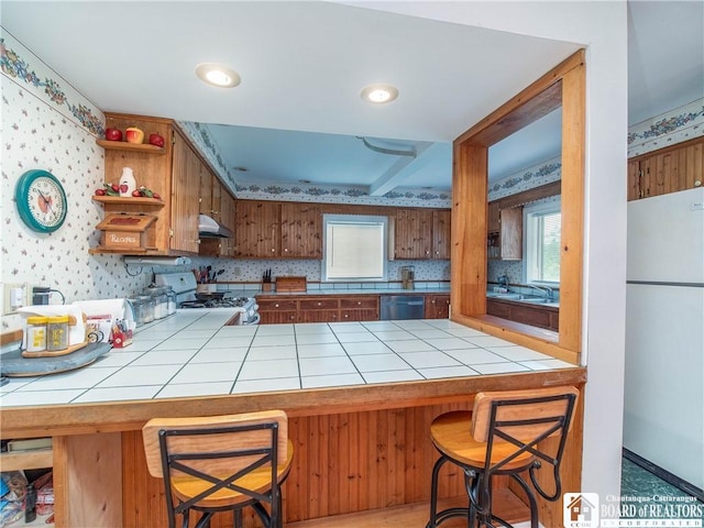 6295 Stockton Hartfield Rd, Chautauqua, NY 14728 - kitchen featuring white appliances, tile countertops, under cabinet range hood, open shelves, and plenty of natural light