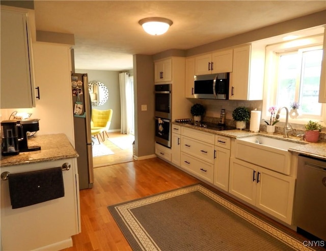 9715 Ethel Rd, Clay, NY 13029 - kitchen with appliances with stainless steel finishes, white cabinetry, light wood-type flooring, light stone countertops, and decorative backsplash