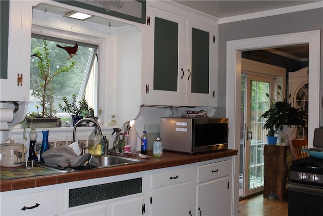 244 State Highway 320, Norwich, NY 13815 - kitchen with stainless steel microwave, tile counters, white cabinetry, ornamental molding, and healthy amount of natural light