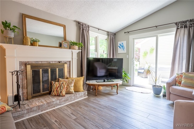 253 Old Oak Post Rd, Amherst, NY 14051 - living room featuring vaulted ceiling, a textured ceiling, wood finished floors, and a brick fireplace