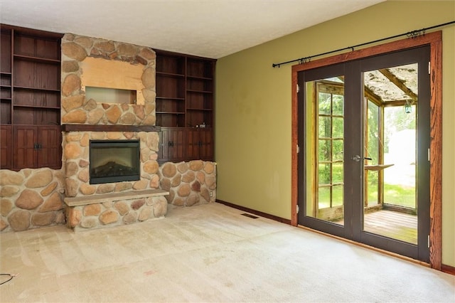 53 Alecia Dr, Greece, NY 14626 - unfurnished living room featuring carpet floors, built in shelves, a stone fireplace, and french doors