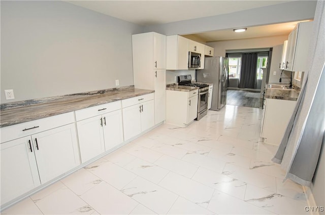 118 Hanover Ave, Salina, NY 13088 - kitchen featuring appliances with stainless steel finishes, light marble finish floors, and white cabinetry