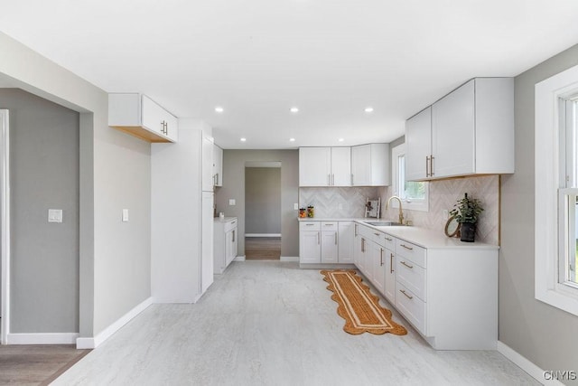 7921 Davis Rd N, Clay, NY 13041 - kitchen with tasteful backsplash, white cabinets, light countertops, light wood finished floors, and recessed lighting