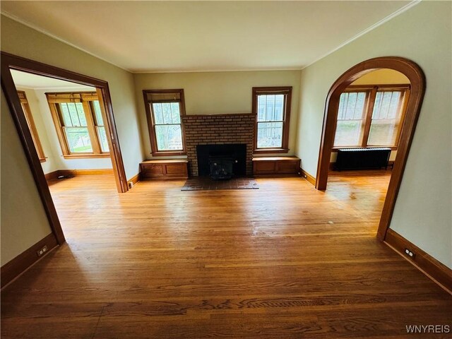 39 Chestnut St, Persia, NY 14070 - unfurnished living room with wood finished floors, ornamental molding, and a brick fireplace