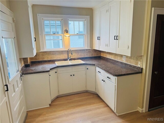 39 Chestnut St, Persia, NY 14070 - kitchen with light wood-style floors, tasteful backsplash, dark countertops, and white cabinets