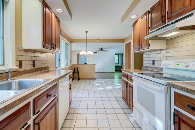 120 Scotch Ln, Irondequoit, NY 14617 - kitchen featuring white appliances, under cabinet range hood, light tile patterned flooring, hanging light fixtures, and backsplash