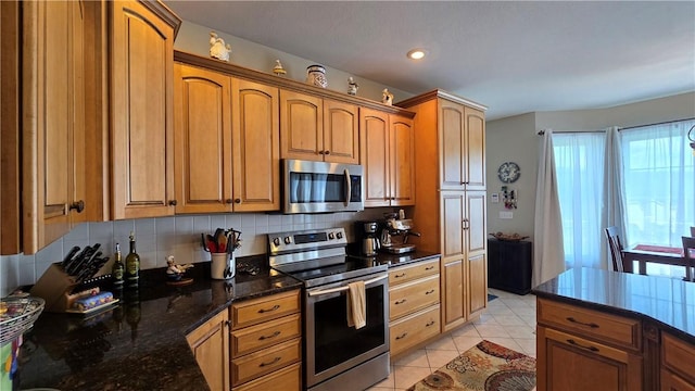 3390 Conhocton Rd, Erwin, NY 14870 - kitchen with stainless steel appliances, light tile patterned floors, decorative backsplash, brown cabinets, and dark stone countertops