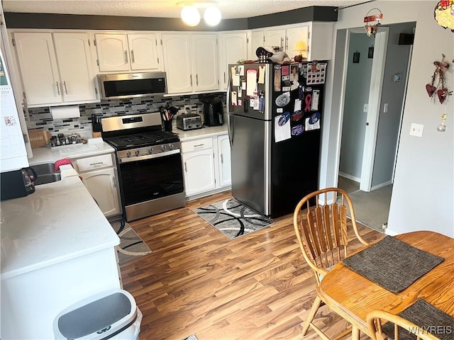 126 Ellicott Creek Rd Unit 5, Tonawanda, NY 14150 - kitchen featuring appliances with stainless steel finishes, decorative backsplash, white cabinetry, light wood-style flooring, and light countertops