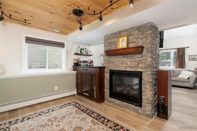 89 Rambling Rd, Amherst, NY 14051 - living area featuring wooden ceiling, a baseboard heating unit, wood finished floors, a stone fireplace, and track lighting