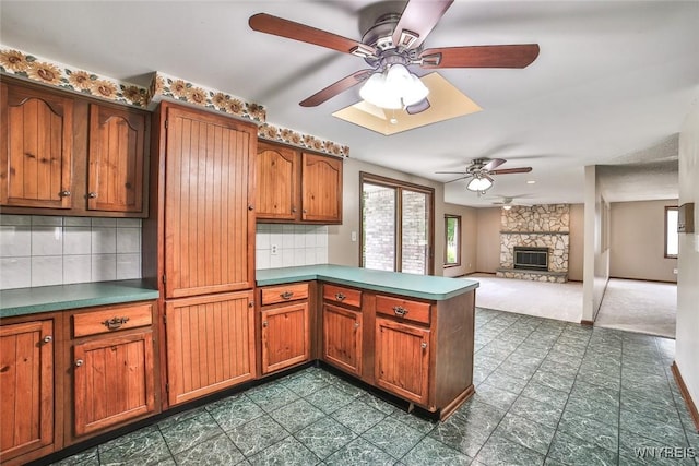 210 Townline Rd, Elma, NY 14059 - kitchen with a peninsula, a ceiling fan, brown cabinets, tasteful backsplash, and a fireplace