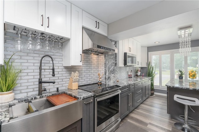 255 Watson Rd, Perinton, NY 14450 - kitchen featuring stainless steel appliances, exhaust hood, white cabinetry, tasteful backsplash, and light stone counters