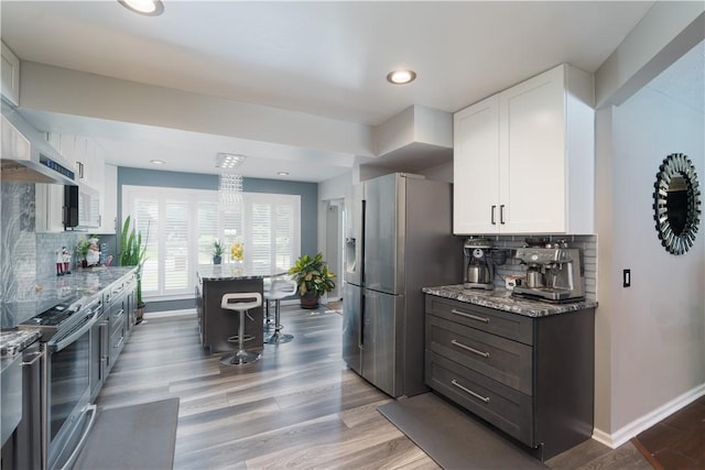 255 Watson Rd, Perinton, NY 14450 - kitchen with stainless steel appliances, light stone counters, a kitchen breakfast bar, white cabinetry, and tasteful backsplash