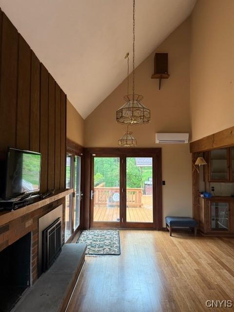 2033 Artemis Dr, Virgil, NY 13045 - unfurnished living room featuring high vaulted ceiling, light wood-style flooring, a brick fireplace, a wall unit AC, and french doors