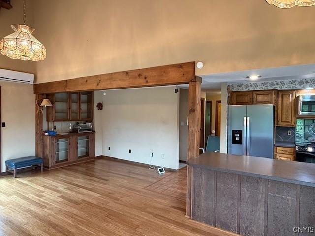 2033 Artemis Dr, Virgil, NY 13045 - kitchen featuring appliances with stainless steel finishes, a high ceiling, dark countertops, a wall mounted AC, and light wood-type flooring