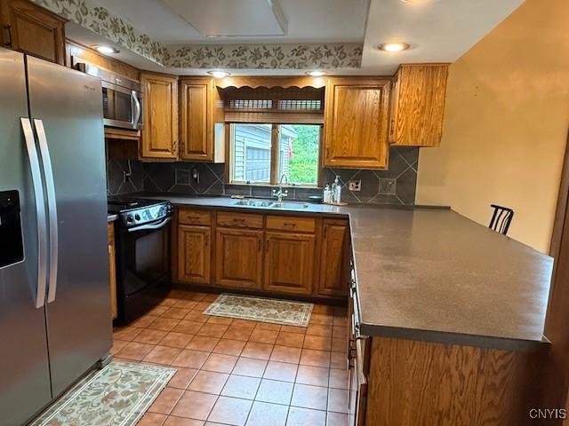 2033 Artemis Dr, Virgil, NY 13045 - kitchen with stainless steel appliances, a peninsula, brown cabinetry, and backsplash