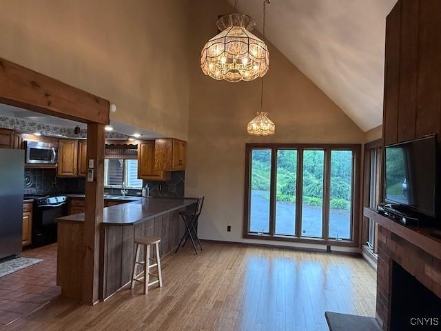 2033 Artemis Dr, Virgil, NY 13045 - kitchen with stainless steel microwave, a chandelier, high vaulted ceiling, freestanding refrigerator, and black stove