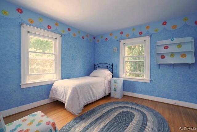 57 Dudley Ave, Hamburg, NY 14075 - bedroom featuring multiple windows, wood finished floors, and wallpapered walls
