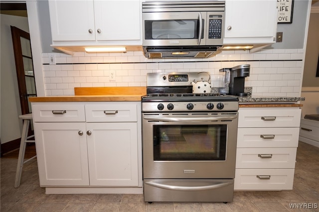 128 Argonne Dr, Tonawanda, NY 14217 - kitchen with stainless steel appliances, white cabinetry, backsplash, and light tile patterned flooring