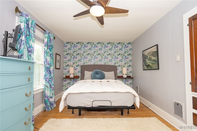 128 Argonne Dr, Tonawanda, NY 14217 - bedroom with wallpapered walls, an accent wall, light wood-type flooring, and a ceiling fan