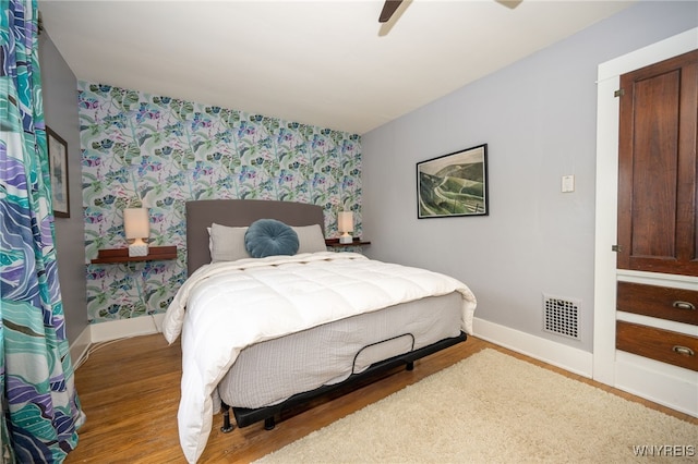 128 Argonne Dr, Tonawanda, NY 14217 - bedroom with wallpapered walls, wood finished floors, ceiling fan, and an accent wall