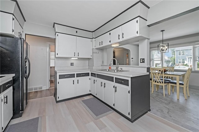 111 Hartsdale Rd, Irondequoit, NY 14622 - kitchen featuring light countertops, a chandelier, arched walkways, white cabinetry, and black fridge with ice dispenser