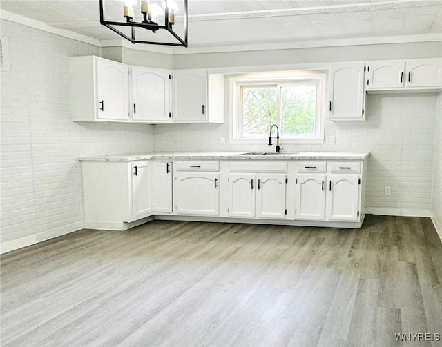 169 Davidson Ave, Buffalo, NY 14215 - kitchen featuring light wood-type flooring, white cabinetry, a chandelier, and light countertops