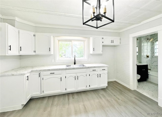 169 Davidson Ave, Buffalo, NY 14215 - kitchen featuring white cabinets, light wood-style floors, a chandelier, light stone countertops, and tasteful backsplash