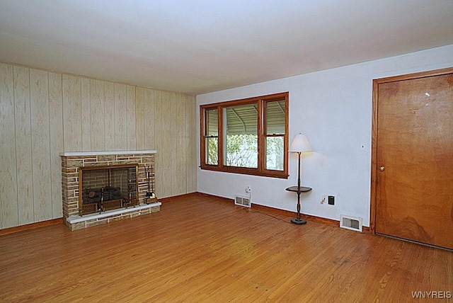107 Singer Dr, West Seneca, NY 14224 - unfurnished living room featuring wood finished floors, wooden walls, and a stone fireplace