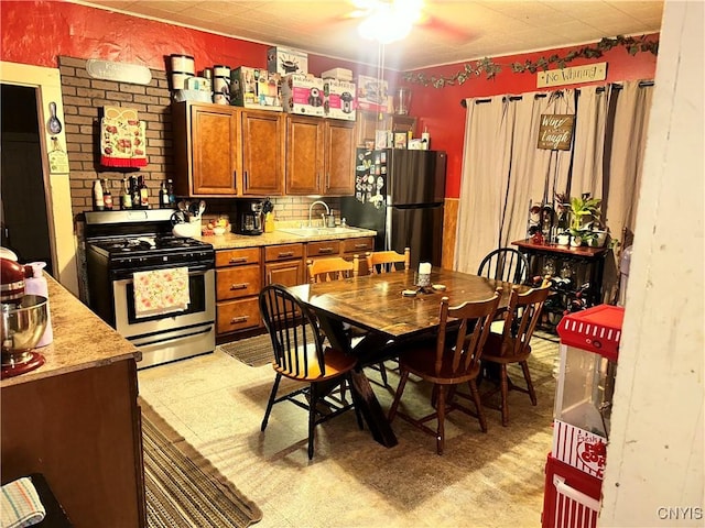 41 Owego St, Cortland, NY 13045 - kitchen with stainless steel gas range oven, freestanding refrigerator, brown cabinetry, a ceiling fan, and light countertops