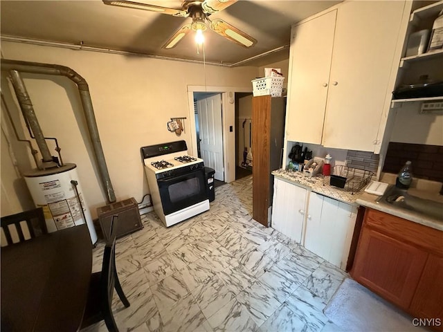 41 Owego St, Cortland, NY 13045 - kitchen featuring range with gas stovetop, a ceiling fan, light marble finish flooring, light countertops, and water heater