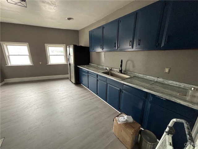 926 Burnet Ave Unit 30, Syracuse, NY 13203 - kitchen with blue cabinets, freestanding refrigerator, light wood finished floors, and light countertops