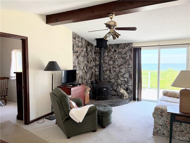 5366 Clark Point Rd, Henderson, NY 13651 - living area with light colored carpet, ceiling fan, a wood stove, and beamed ceiling