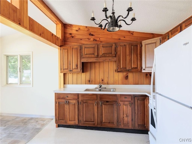 5366 Clark Point Rd, Henderson, NY 13651 - kitchen featuring freestanding refrigerator, a chandelier, light countertops, brown cabinetry, and wooden walls