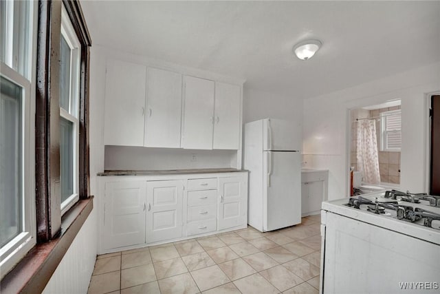 214 Ludington St, Buffalo, NY 14206 - kitchen featuring white appliances, white cabinets, light tile patterned floors, and light countertops