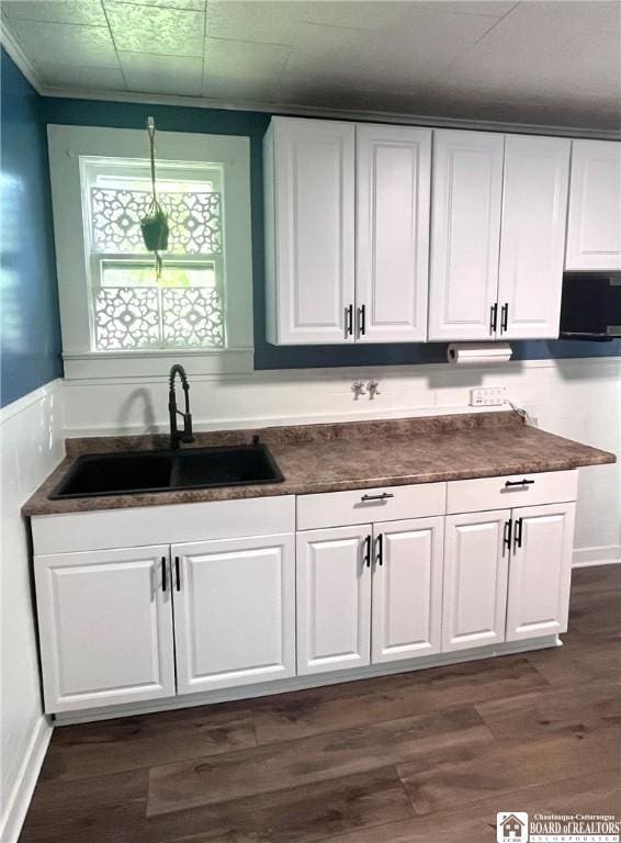 1504 River St, Olean, NY 14760 - kitchen featuring white cabinets, dark countertops, dark wood-type flooring, and a wainscoted wall