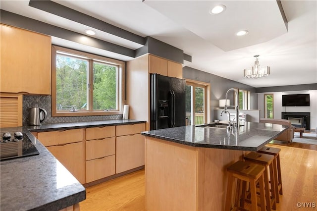 3313 Thompson Rd, Cazenovia, NY 13035 - kitchen featuring black refrigerator with ice dispenser, open floor plan, dark stone countertops, light brown cabinetry, and light wood-style flooring