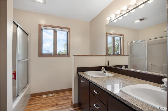 3313 Thompson Rd, Cazenovia, NY 13035 - bathroom featuring wood finished floors, double vanity, and combined bath / shower with glass door