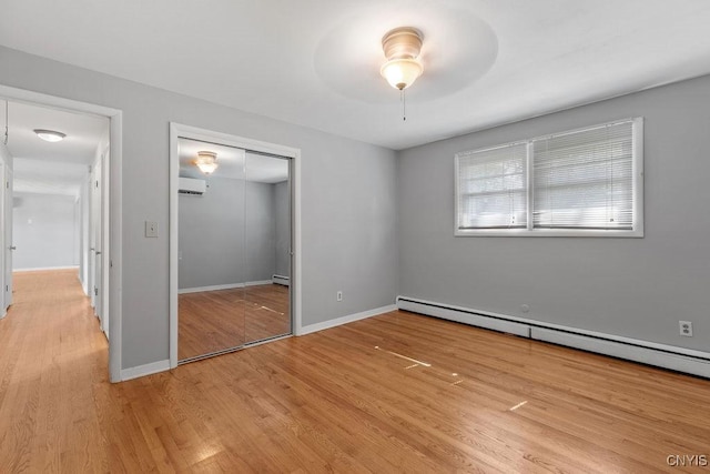 113 Craig Cir, Dewitt, NY 13214 - unfurnished bedroom featuring baseboard heating, light wood-style flooring, a closet, a wall mounted AC, and a ceiling fan