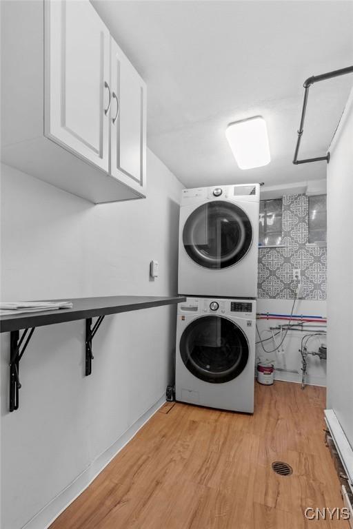 113 Craig Cir, Dewitt, NY 13214 - laundry room featuring stacked washer and clothes dryer, cabinet space, and light wood-type flooring