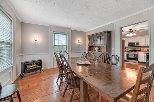 6188 Lake St, Aurelius, NY 13034 - dining area with light wood finished floors, a textured ceiling, ceiling fan, a wainscoted wall, and ornamental molding