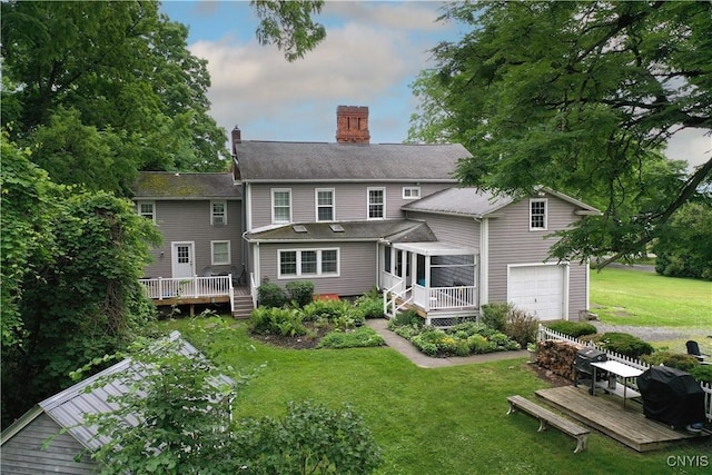 6188 Lake St, Aurelius, NY 13034 - back of house featuring a wooden deck, an attached garage, a chimney, a lawn, and a sunroom