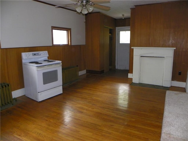 202-204-206 N Monroe St, Reading, NY 14891 - kitchen featuring white electric stove, radiator, ceiling fan, healthy amount of natural light, and wooden walls