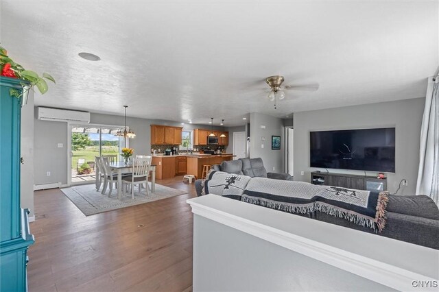 13489 Case Rd, Lyme, NY 13622 - living area with a wall mounted air conditioner, a baseboard heating unit, a ceiling fan, wood finished floors, and a chandelier