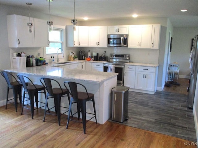 7739 Roberts St, Lenox, NY 13032 - kitchen featuring stainless steel appliances, a kitchen breakfast bar, a peninsula, white cabinetry, and wood finished floors