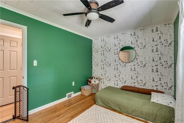266 Chestnut St, Watertown City, NY 13601 - bedroom featuring crown molding, an accent wall, wood finished floors, and ceiling fan