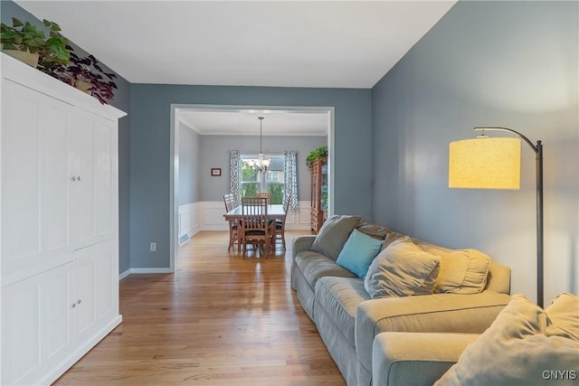 8879 Kilkenny Dr, Lysander, NY 13027 - living area featuring a chandelier, light wood-style floors, ornamental molding, and a wainscoted wall