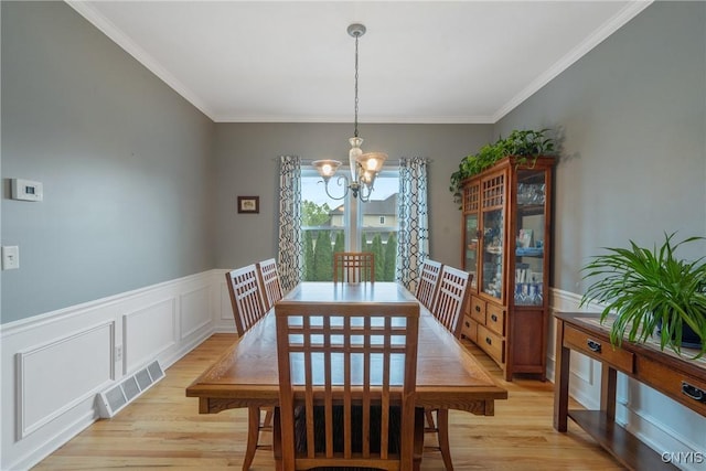8879 Kilkenny Dr, Lysander, NY 13027 - dining area featuring a chandelier, light wood-style floors, crown molding, a wainscoted wall, and a decorative wall