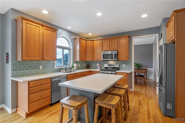 8879 Kilkenny Dr, Lysander, NY 13027 - kitchen with appliances with stainless steel finishes, light wood finished floors, light countertops, a breakfast bar area, and tasteful backsplash
